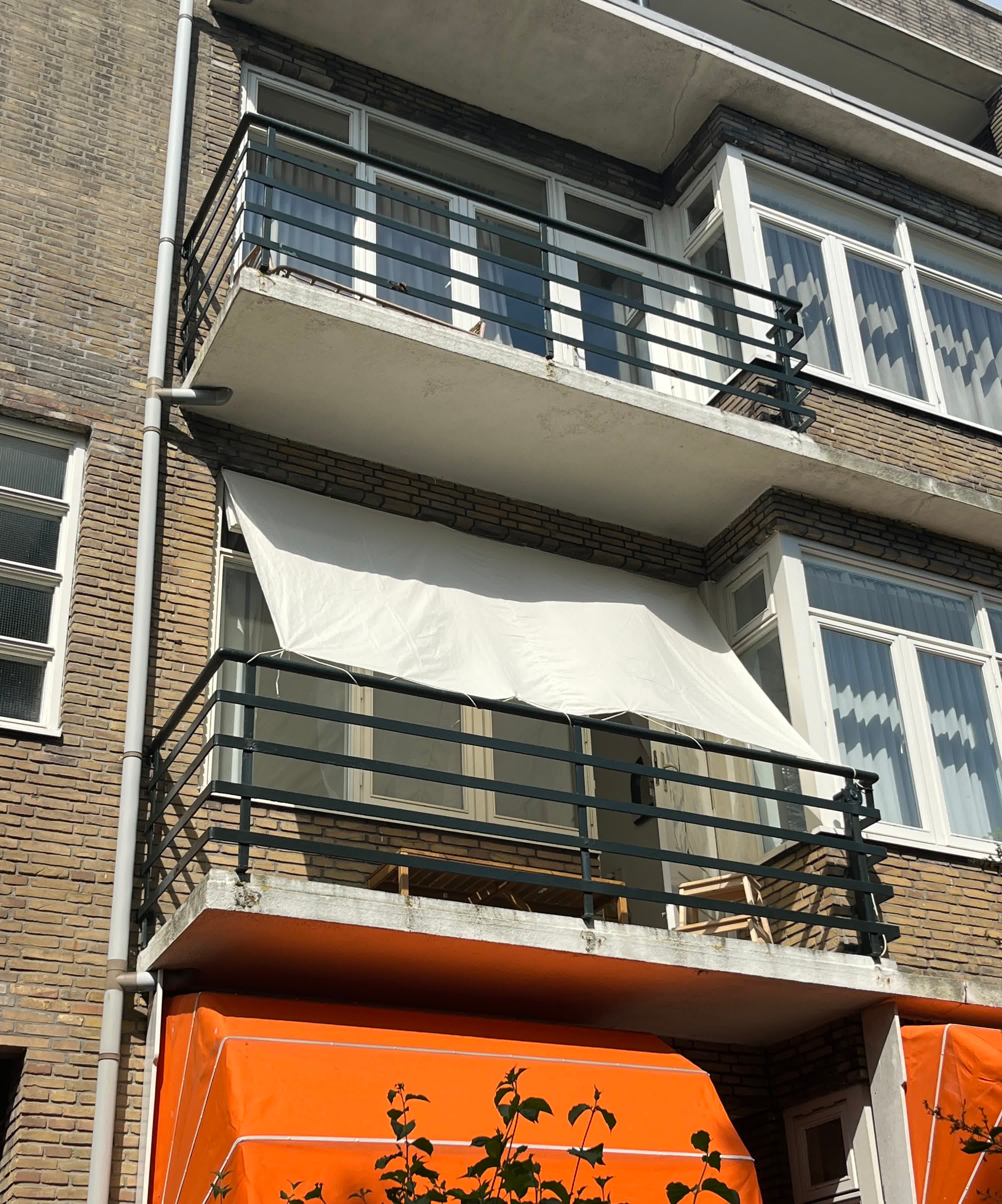 the facade of a house with a balcony that has a D.I.Y shade awning attached to it